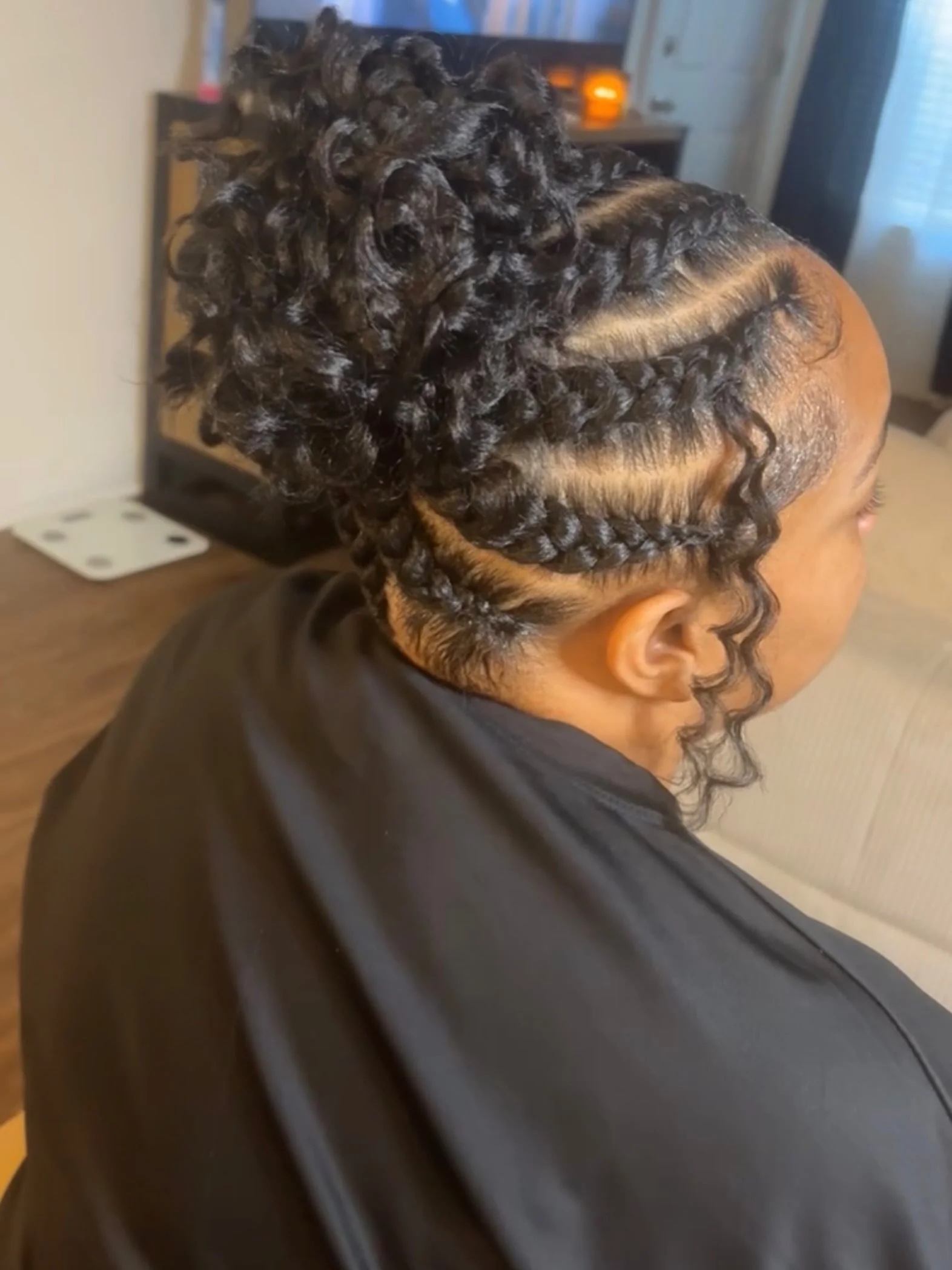 Cornrows with a ringlet bun and a side tendril