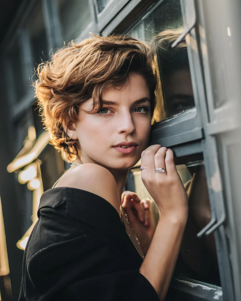 Woman with a modern medium-length shag haircut, airy choppy layers, soft curtain bangs, and natural brunette waves, photographed from the front in a bright salon.