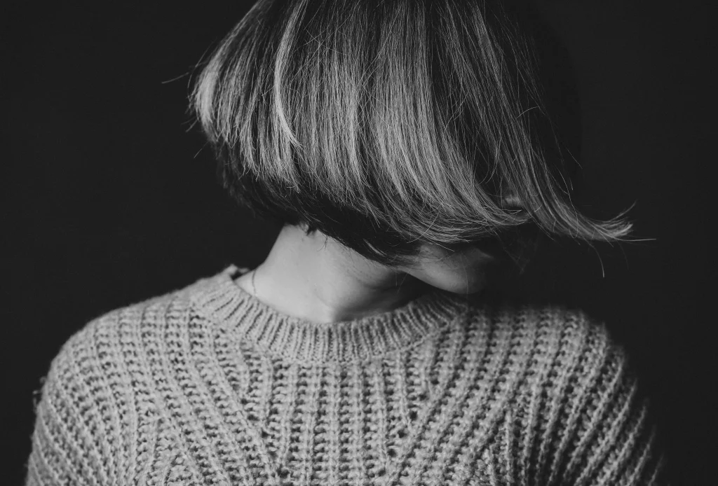 Woman with a modern graduated bob haircut, softly stacked shorter layers at the nape, slightly longer front pieces, glossy chestnut hair, side-front view.