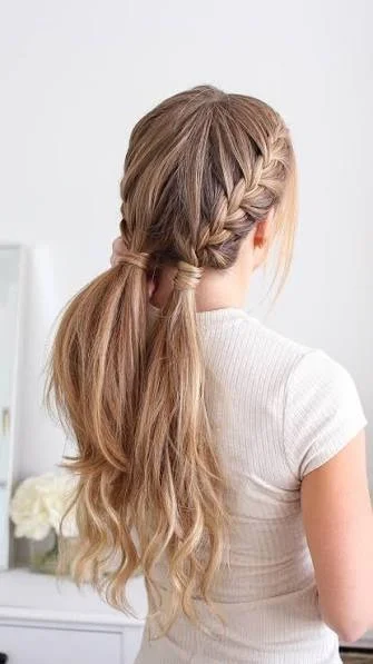Two symmetrical Dutch braids with raised woven sections on long dark blonde hair, clean center part, casual sporty look, rear three-quarter view, natural daylight.
