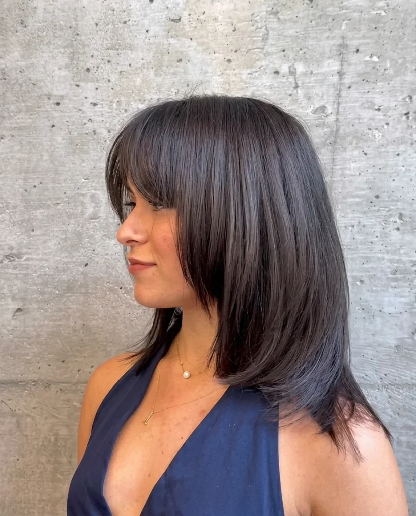 Medium-length cub cut with sleek layers and side-swept bangs, side profile