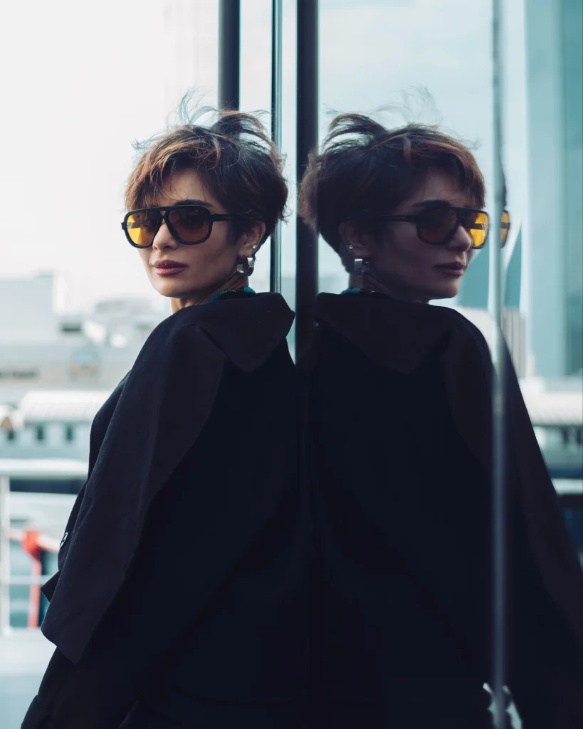 Woman with a textured bixie haircut combining a short pixie silhouette and bob-like length around the ears, wispy fringe, softly tousled dark hair, editorial portrait.