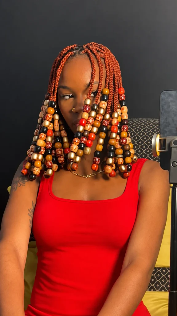Copper-red box braids with chunky wooden beads in gold, red and black