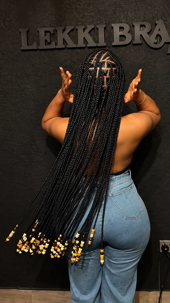 Hip-length knotless braids with triangle parts and gold and brown tip beads