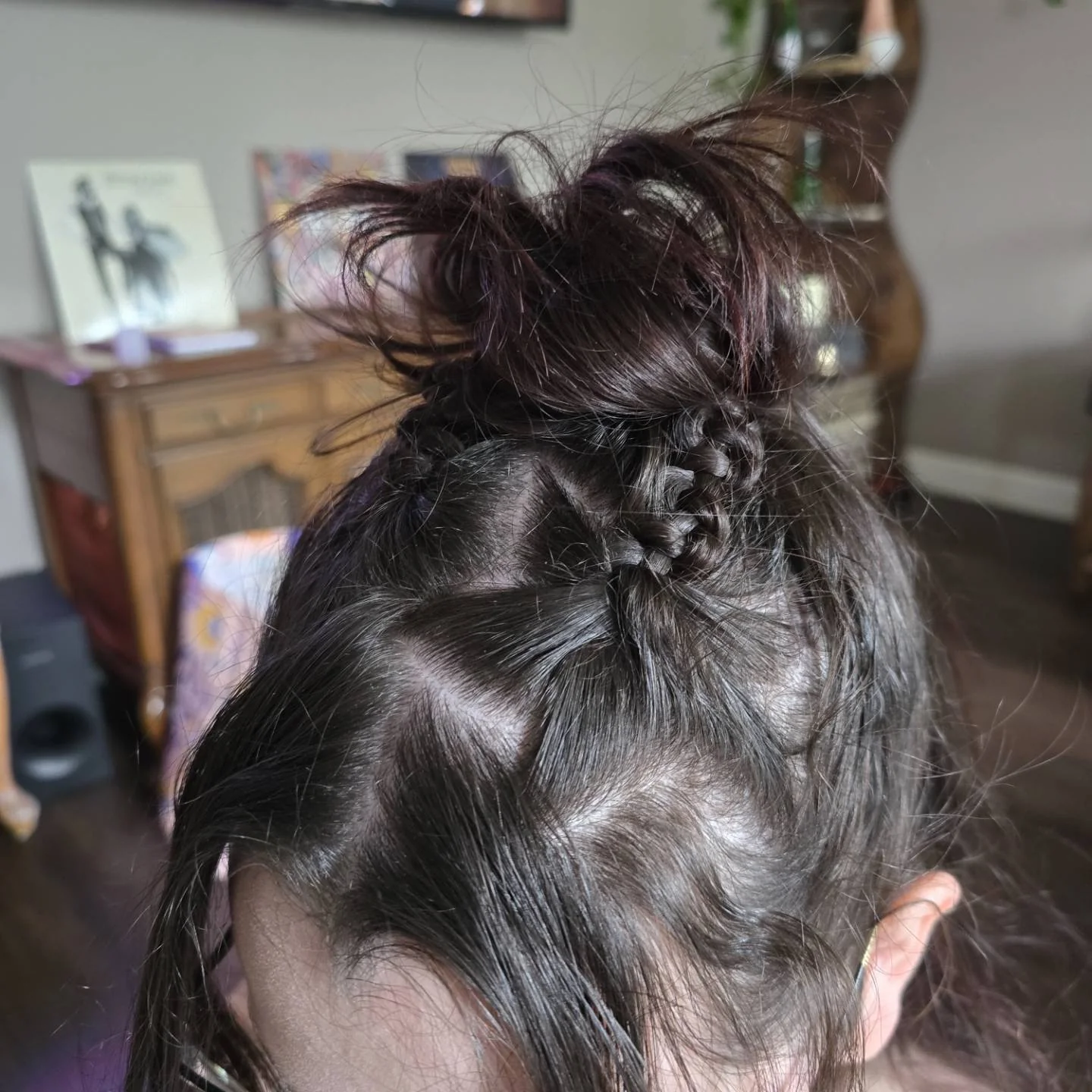 Dark hair with small braids leading into a messy top knot